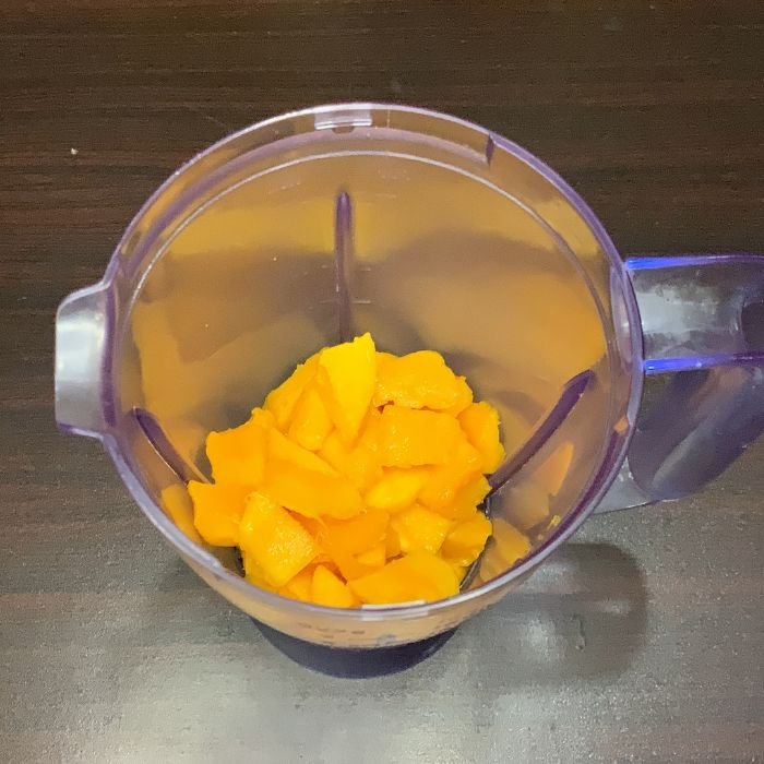Adding mango to a mango lassi blending jug