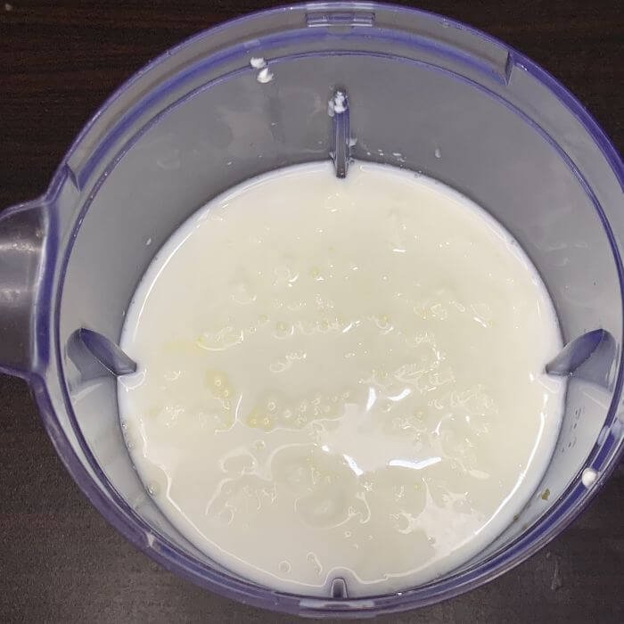 Adding milk To a mango lassi blending jug